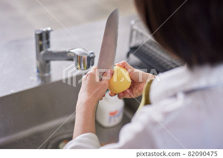 Young woman removing potato sprouts in the kitchen 82090475