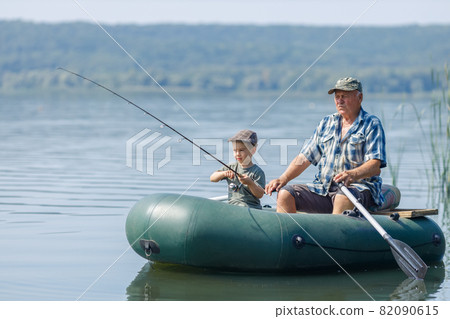 grandfather with grandson together fishing from inflatable boat grandfather with grandson together fishing from inflatable boat 82090615