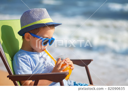 little boy drinking juice on sea beach little boy drinking juice on sea beach 82090635