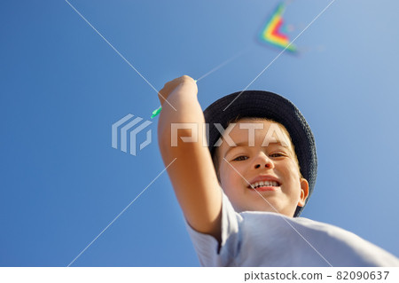 portrait of smiling little boy with flying colorful kite 82090637