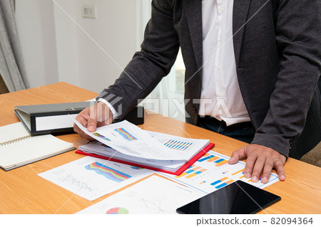 Asian young businessman holding summary report paper checking sales data chart 82094364