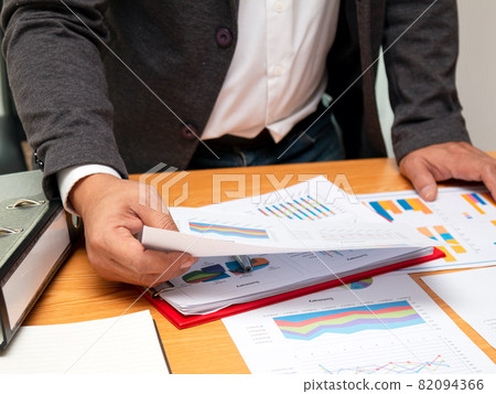 Asian young businessman holding summary report paper checking sales data 82094366