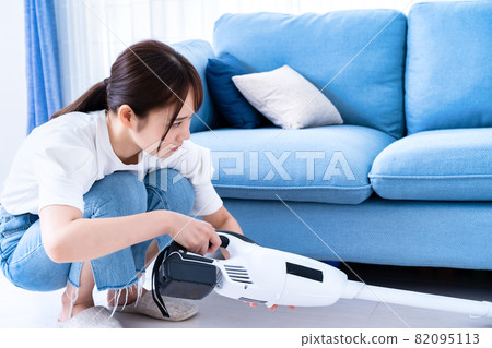Woman vacuuming in the living room 82095113