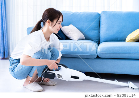 Woman vacuuming in the living room 82095114