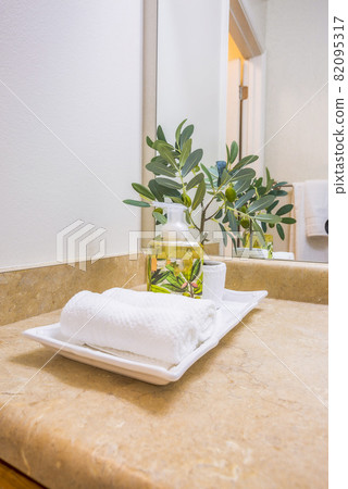 Countertop with towels soap and plant on tray against white wall and mirror 82095317