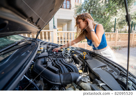 Young woman is looking to open car hood for troubleshoot. Transportation and vehicle concept. Young woman is looking to open car hood for troubleshoot. Transportation and vehicle concept. 82095520