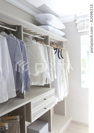 white shirts, pants and blouses hanging in closet 82096318