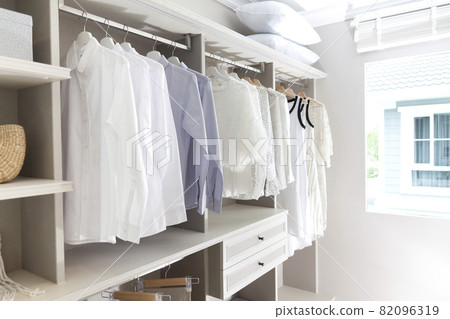 white shirts, pants and blouses hanging in closet 82096319