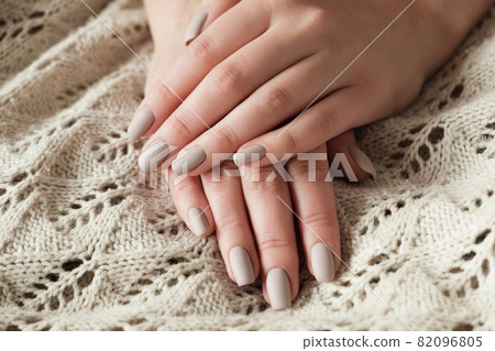 Matt nude beige nails close up. Winter or autumn manicure, woman hand on warm sweater Matt nude beige nails close up. Winter or autumn manicure, woman hand on warm sweater 82096805