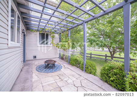 Paved exterior patio with wooden pergola near sunset 82097013