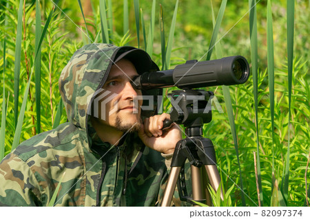 man ornitologist makes observations in the wild with a spotting scope man ornitologist makes observations in the wild with a spotting scope 82097374