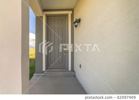 Close up of home entrance with gray front door and lantern on the concrete wall Close up of home entrance with gray front door and lantern on the concrete wall 82097409