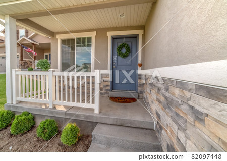 Facade of a home with railing on the porch and front door decorated with wreath 82097448