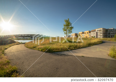 Roads and grassy ground with buildings and bridge over lake view on a sunny day 82097470