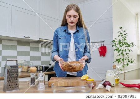Young woman in the home kitchen cooking meat, chicken 82097985