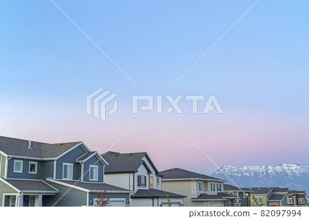 Exterior of homes and mountain with snowy peak against cloudy blue sky at sunset Exterior of homes and mountain with snowy peak against cloudy blue sky at sunset 82097994