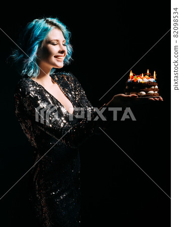Birthday party. Happy woman. Holiday organization. Enjoying celebration. Inspired joyful lady blue hair holding festive cake candle lights isolated black. Birthday party. Happy woman. Holiday organization. Enjoying celebration. Inspired joyful lady blue hair holding festive cake candle lights isolated black. 82098534