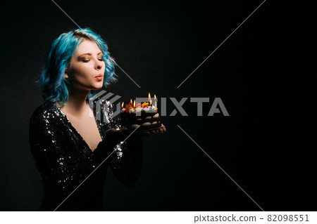 Enjoying birthday. Dreamful woman. Holiday wish. Advertising background. Inspired lady blue hair blowing candle lights on festive cake isolated black copy space. Enjoying birthday. Dreamful woman. Holiday wish. Advertising background. Inspired lady blue hair blowing candle lights on festive cake isolated black copy space. 82098551