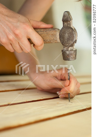 Female hands are using claw hammer and nail for making wooden bench, gender equality, feminism, do it yourself concepts. Female hands are using claw hammer and nail for making wooden bench, gender equality, feminism, do it yourself concepts. 82098777