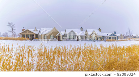Home facade with snowy roofs and surrounded by snow covered ground in winter Home facade with snowy roofs and surrounded by snow covered ground in winter 82099324
