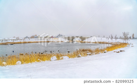 Lake and arched bridge surrounded by snow covered terrain in winter Lake and arched bridge surrounded by snow covered terrain in winter 82099325