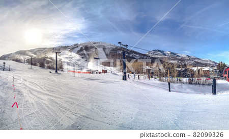 Ski resort with ski lifts under a cloudy blue sky on a sunny winter day Ski resort with ski lifts under a cloudy blue sky on a sunny winter day 82099326