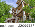Townhomes balconies with columns and lattice railings against trees and sky 82099327