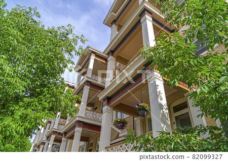 Townhomes balconies with columns and lattice railings against trees and sky Townhomes balconies with columns and lattice railings against trees and sky 82099327