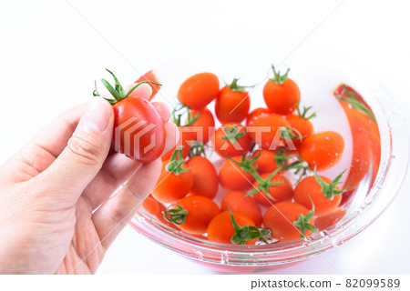 Put water in a glass plate and wash the cherry tomatoes with running water. Hold the cherry tomatoes in your hands. 82099589