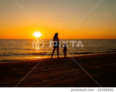 Young woman and little girl hold hands by the sea. Young woman and little girl hold hands by the sea. 82099680