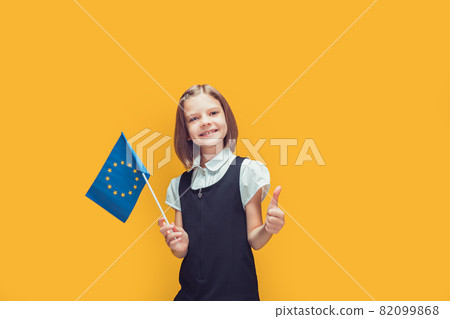 Smiling schoolgirl with the flag of European Union showing thumb-up. Education in Europe concept Smiling schoolgirl with the flag of European Union showing thumb-up. Education in Europe concept 82099868