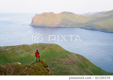 Tourist enjoying the view of Vagar Island from Mount Sornfelli in Faroe Islands 82100376