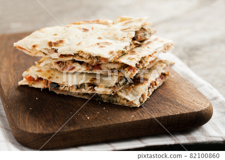 pile of quesadillas with chicken and vegetables on the rustic board 82100860