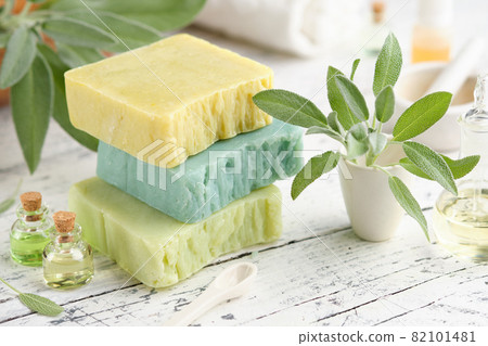 Homemade natural organic soap bars, bottles of essential oil and fresh green sage leaves on white table. Homemade natural organic soap bars, bottles of essential oil and fresh green sage leaves on white table. 82101481