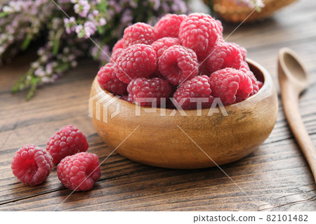 Wooden bowl of fresh red raspberries on kitchen table. Wooden bowl of fresh red raspberries on kitchen table. 82101482