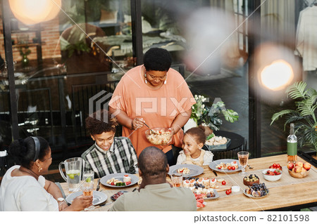 Happy Grandmother Serving Food at Dinner 82101598