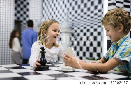 Tweenagers solving conundrum in lost room designed as chessboard Tweenagers solving conundrum in lost room designed as chessboard 82102487