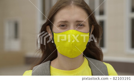 Young girl schoolgirl smiling in a protective mask, coronavirus pandemic, covid 19, safe walking around the city, helps from infections and dust, air filtration, keep healthy people safe, concept 82103191