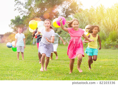 Kids with balloons running through field Kids with balloons running through field 82103336