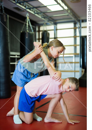 Boy and girl in pair exercising self-defense movements 82103466