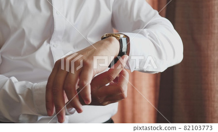 A man looks at the dial of the clock on his hand, to check the time, to be late for work in the morning, the businessman is punctual, the business plan is on time A man looks at the dial of the clock on his hand, to check the time, to be late for work in the morning, the businessman is punctual, the business plan is on time 82103773