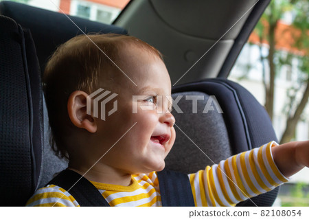 Happy baby boy sitting in car seat.  82108054