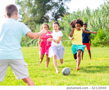 Happy preteen girls and boys playing football on green lawn Happy preteen girls and boys playing football on green lawn 82110040