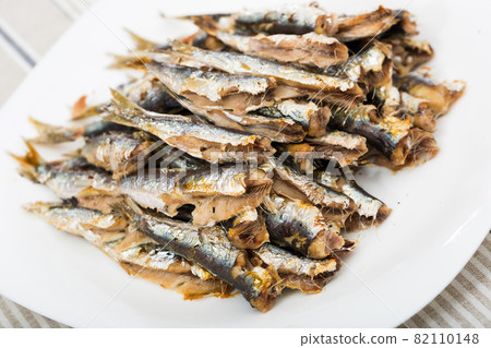Dish of many tasty baked in oven anchovy served on plate at table 82110148