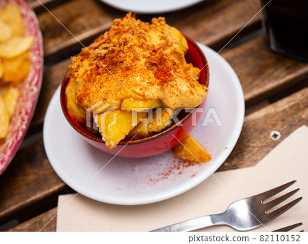 Patatas bravas with sauce, fried bacon pieces and paprika 82110152