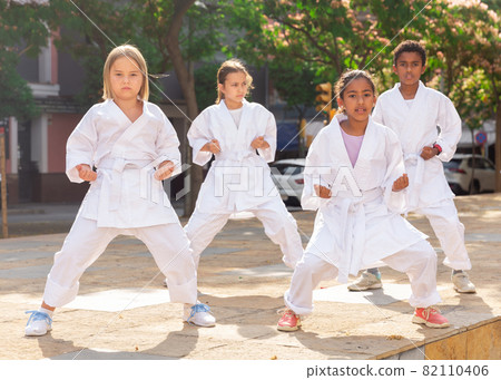 Kids in kimono doing kata outdoors 82110406
