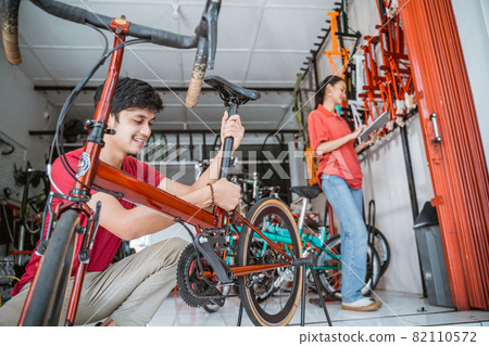 man installs bicycle seatpost with woman in the background man installs bicycle seatpost with woman in the background 82110572