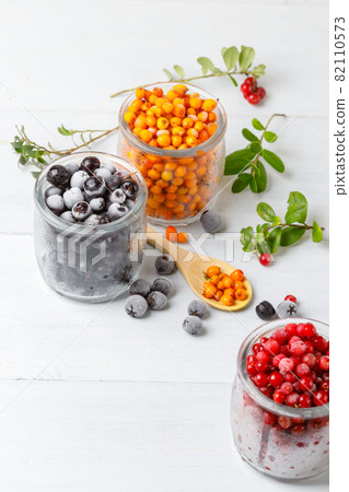 Frozen wild berries in glass jars. Close-up on a white background, vertical frame 82110573