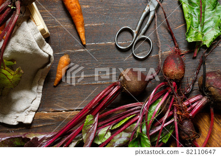 Raw beetroot with tops and carrots on a rough wooden surface. Close-up, top view, horizontal 82110647