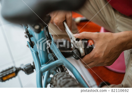 close up of a mechanic's hand installing a pedal using a wrench close up of a mechanic's hand installing a pedal using a wrench 82110692